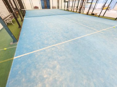 Boş raket tenis kortu, kapalı bir barakanın ışıkları açık ve oyuncuları yok. Yüksek kalite fotoğraf