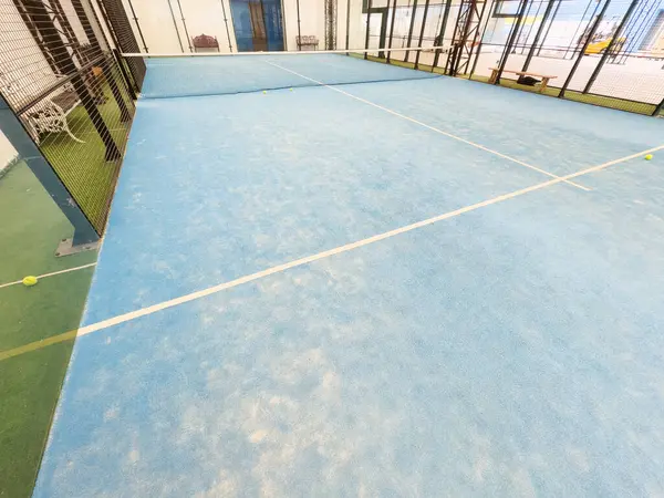 Boş raket tenis kortu, kapalı bir barakanın ışıkları açık ve oyuncuları yok. Yüksek kalite fotoğraf