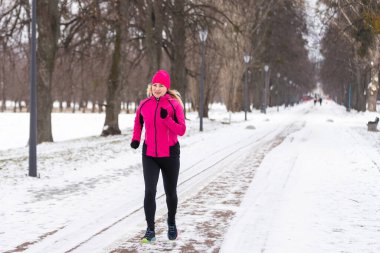 Açık hava spor egzersizleri, spor kıyafetleri fikirleri. Sıcak spor giysili bir kadın kış boyunca dışarıda koşuyor. Yüksek kalite fotoğraf