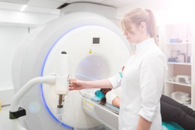 Modern hastane laboratuvarında bir hastaya tıbbi tomografi ya da MRI taraması yapın. Radyografi bölümünün içi. Beyaz odada teknolojik olarak gelişmiş ekipmanlar var. Manyetik rezonans tanılama makinesi.
