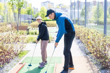 Golf tecrübelerimle paylaşıyorum. Neşeli genç bir adam kızına gündüz vakti mini golf oynamayı öğretiyor. Arkadaş canlısı aile kavramı. Yüksek kalite fotoğraf