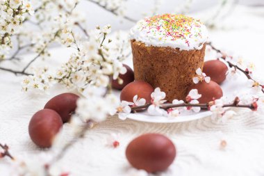 Paskalya kompozisyonu. Çiçekli bir kayısı dalı, boyanmış yumurtalar ve şeker parçacıklarıyla süslenmiş paskalya pastası..