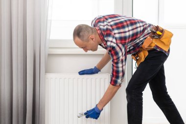 İş yerindeki tesisatçı. Su ısıtma radyatörü kuruluyor. Yüksek kalite fotoğraf
