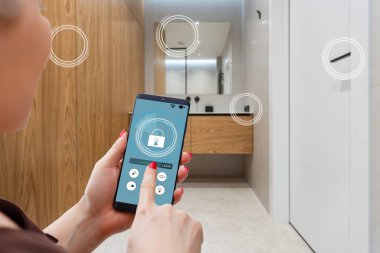 Akıllı ev, ev otomasyonu, uygulama simgeli aygıt. Kadın akıllı telefonunu akıllı güvenlik uygulaması ile evinin kapısını açmak için kullanıyor.
