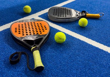 Turuncu bir padel raketi ve mavi bir kortun zemininde bir top. Padel konsepti. Kürek takımı. Yüksek kalite fotoğraf