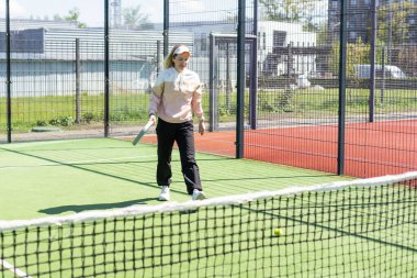 Genç, sportif bir kadın, raket tenisi antrenmanı sırasında basit hareketler yapıyor. Yüksek kalite fotoğraf