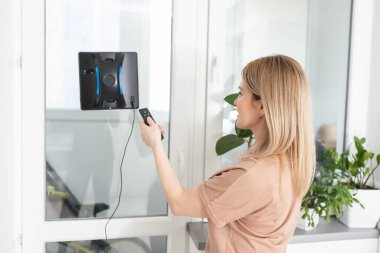 Yüksek bina açık havada elektrikli süpürge robot temizleme penceresi. genç kadın uzaktan kumanda