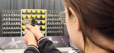 Genç bir kız silahla atış talimi yapıyor. Yüksek kalite fotoğraf