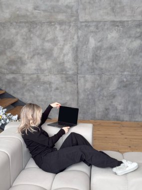 Uzaktan kumanda. Evde otururken dizüstü bilgisayar kullanan gülümseyen genç bir kadın, bilgisayarla uzaktan öğrenmenin ya da internetteki işin ya da kopyalamanın tadını çıkaran Millennial Woman çalışıyor ya da uzaktan çalışıyor. Yüksek kalite fotoğraf