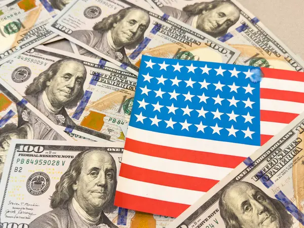  100 dolarlık banknot ve Amerikan bayrağının arka planında duran bir evin koşullu görüntüsü. Yüksek kalite fotoğraf