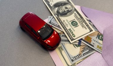 Üzerinde dolar banknotları olan bir zarf ve beyaz bir araba, ulaşım maliyeti planlama konsepti. Yüksek kalite fotoğraf