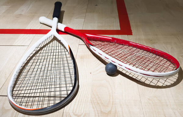 Two rackets and two squash balls lie on the parquet floor. Horizontal photo. High quality photo