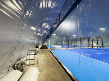  Geniş modern bir yapı altında, yeni kurulmuş padel kortları. Merkezde mahkemelerin girişi var, bir tarafta. Yüksek kalite fotoğraf