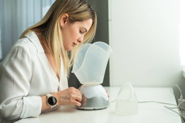 Siyah arka planda tıbbi buharlaştırıcı nebulizör makinesiyle solunum yapan genç bir kadın. Yüksek kalite fotoğraf