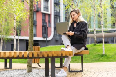 Şehirde dizüstü bilgisayarda çalışan genç bir iş kadını. Yüksek kalite fotoğraf