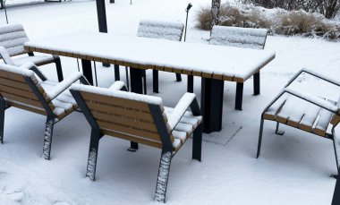 Açık hava mobilyaları kışın karla kaplıdır. Kar yağarken veranda ve bahçe. Hiç kimse, sokak fotoğrafı, seçici odak. Yüksek kalite fotoğraf