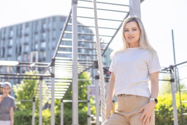 Genç sarışın kadın caddede kendine güvenen bir şekilde gülümsüyor. Yüksek kalite fotoğraf