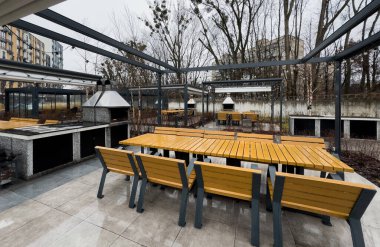 Açık hava pergola gölgelik yapısı, tente ve teras çatısı, yemek masası, sandalyeler, peyzaj ile çevrili metal ızgara. Yüksek kalite fotoğraf