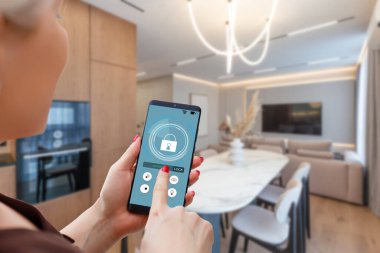 Akıllı ev otomasyon uygulaması arka planda iç mekan olan kadın eliyle akıllı telefondan tutulmuş. Yüksek kalite fotoğraf