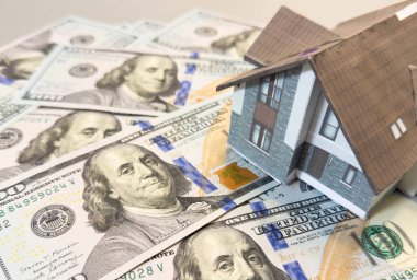 Amerikan doları banknotlarının arka planında ev modeli. Konut piyasası, emlak satın alma veya kiralama kavramı. Yüksek kalite fotoğraf