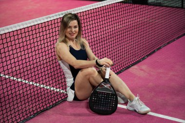 Padel kortunda yerde raketle uzanan genç bir kadın. Yüksek kalite fotoğraf