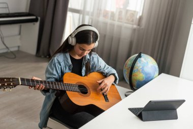 Kız online gitar dersleri veriyor, evden internet üzerinden konsept çalışması yapıyor. Yüksek kalite fotoğraf