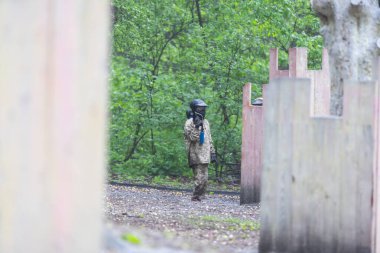 Paintball oyunu. Silahlı oyuncular boya topu atıyorlar. Çocuk parkındaki adamlar. Kamuflajlı ve maskeli adamlar kavga ediyor. Yüksek kalite fotoğraf