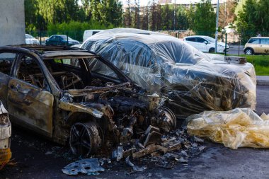 Otoparkta kırık ve yanmış arabalar, kaza ya da kasıtlı vandalizm. Yanmış araba. Bir araba kazasının sonuçları. Kundaklama yüzünden zarar görmüş. Rus birlikleri tarafından Ukrayna 'da vurulan sivil araçlar.