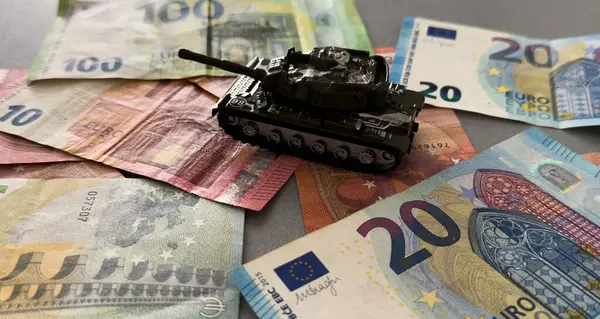 Savaşı finanse etme kavramı. Oyuncak tank, euro, saat. Yüksek kalite fotoğraf