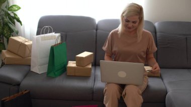 İş yerinde dizüstü bilgisayar kullanan, internetteki kadın girişimci paket kutuları hazırlayan, ekommerce postasını kontrol eden çevrimiçi perakende satış ve ticaret mağazası siparişi teslimat deposunda yerine getirildi..