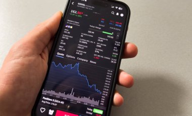 Kyiv, Ukrayna - 20 Mart 2025: Borsa verilerini kontrol etmek için cep telefonu kullanan bir işadamı. Yüksek kalite fotoğraf