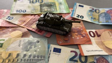 Savaşı finanse etme kavramı. Oyuncak tank, euro, saat. Yüksek kalite fotoğraf