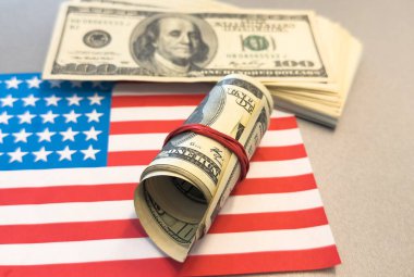 Amerikan bayrağı. Bayrağın altında borsa fiyatları grafiği. Yıldızların üzerinde çaprazlama duran 100 dolarlık banknotu yuvarladı. Diyagramda iki çizgi var. Borsa ticareti kavramı. Yüksek kalite fotoğraf