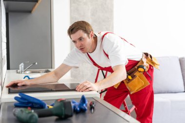 craftsman installs hob in kitchen. Household Appliance Installation Services Concept.