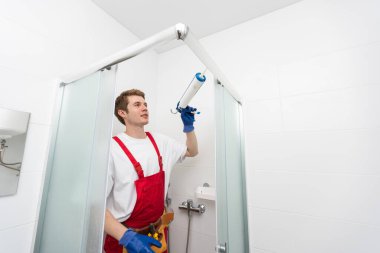 Genç adam banyoda duş kabinin kapısı tamiri