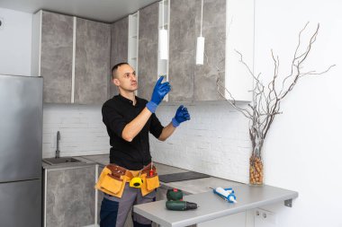 Elektrikçi tavan lambasını yerleştiriyor, kabloları yerleştiriyor. Yüksek kalite fotoğraf