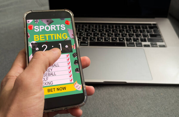 Man betting on sports, holding smart phone with working online betting mobile application. High quality photo