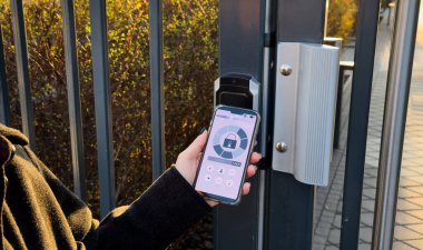 Genç ve şık bir kadın dahili telefona akıllı telefon ekleyerek binaya giriyor. Modern güvenlik teknolojileri ve akıllı ev kavramı. Yüksek kalite fotoğraf