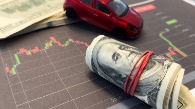  Arabanın arka planında grafikler ve nakit para. Düşen araba piyasası, sigorta, daha düşük fiyatlar, tamir masrafları. Yüksek kalite fotoğraf