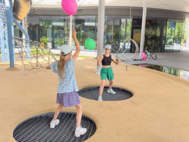 Oyun parkında oynayan ve sallanan iki kız arkadaş. Yüksek kalite fotoğraf