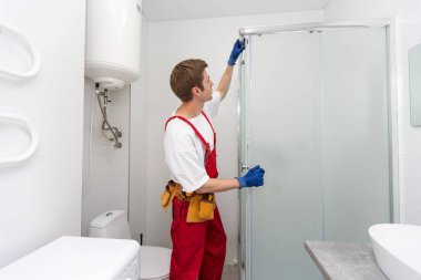 Tesisatçı banyoya duş kabini kuruyor..