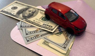 Üzerinde dolar banknotları olan bir zarf ve beyaz bir araba, ulaşım maliyeti planlama konsepti. Yüksek kalite fotoğraf