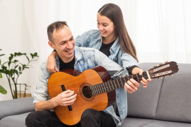 Baba, genç kıza evde gitar çalmayı öğretiyor. Telli müzik aleti olan aile müzik dersleri. Yüksek kalite fotoğraf