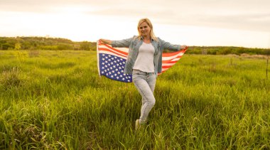 Ülke, vatanseverlik, bağımsızlık günü ve halk konsepti - Ulusal Amerikan bayrağıyla mutlu bir genç kadın sahada.