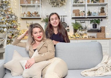 Mutlu aile Noel 'de mutluluğu paylaşır. Anne, sevgili çocuğundan Noel gününde hediyeler alır. Gülümseyen kız, arka planda süslemeli ağaçla birlikte anneye oturma odasında hediye veriyor. Yüksek kalite fotoğraf