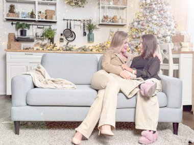 Mutlu aile Noel 'de mutluluğu paylaşır. Anne, sevgili çocuğundan Noel gününde hediyeler alır. Gülümseyen kız, arka planda süslemeli ağaçla birlikte anneye oturma odasında hediye veriyor. Yüksek kalite fotoğraf