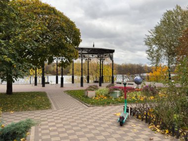 Elektrikli scooter, sonbahar sokağında arka planda ağaçların üzerine park edilmiş. Sonbahar parkına kadar elektrikli scooter, ekolojik ulaşım. Çevre dostu şehir ulaşımı konsepti, scooter kiralama. Yüksek kalite fotoğraf