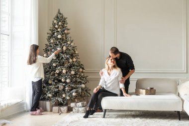 Mutlu Noeller ve mutlu tatiller. Anne, baba ve çocuk hediye değiş tokuşu. Ebeveynler ve kızları kapalı alanda eğleniyorlar. Odada hediyeleri olan sevgi dolu bir aile. Yüksek kalite fotoğraf