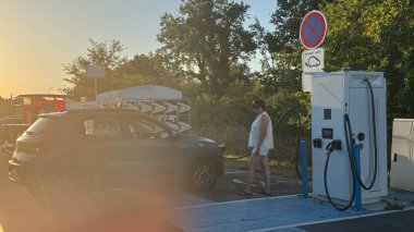 Kadın, elektrikli aracını şarj ederken şarj istasyonunu açıyor. Rahat yaşam için akıllı teknolojiler kavramı, EV arabalar. Yüksek kalite fotoğraf