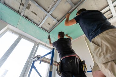 İşçiler paneli tavan çerçevesine yerleştiriyorlar. Yüksek kalite fotoğraf